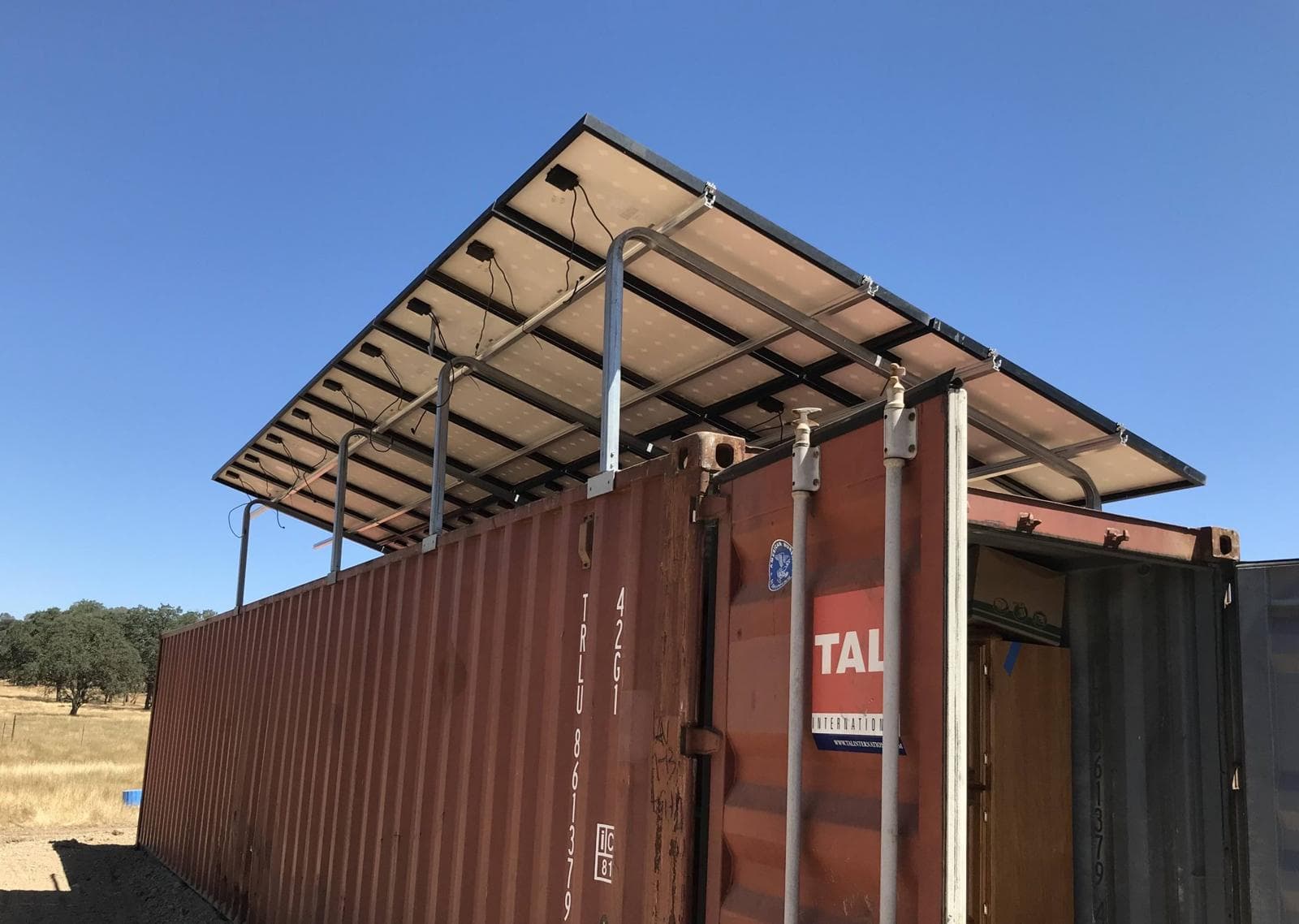 Solar array raised above a 40 ft shipping container on SunnyCal supports